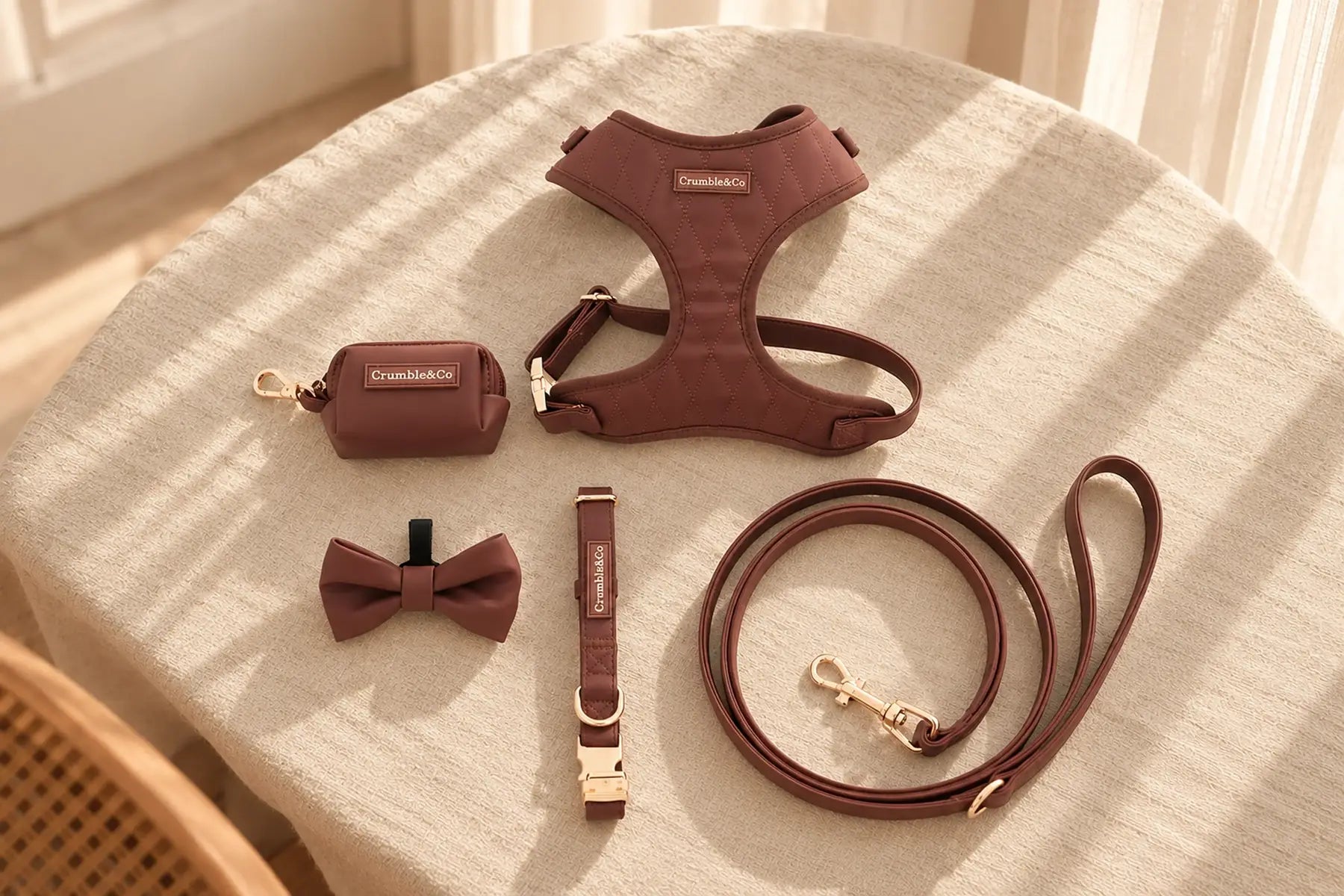 The Espresso set laid out on a linen tablecloth: harness, lead, collar, poo bag holder and bow tie.